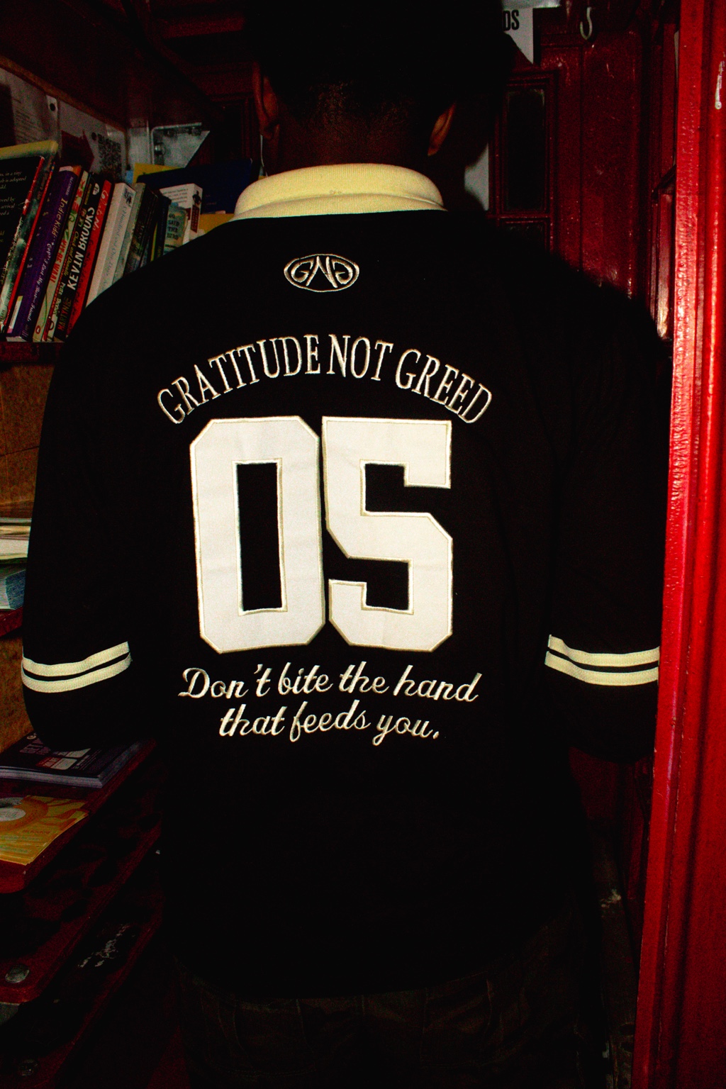 GNG campaign — 05 back of the black rugby polo, Don't bite the hand that feeds you embroidery, at a London book exchange