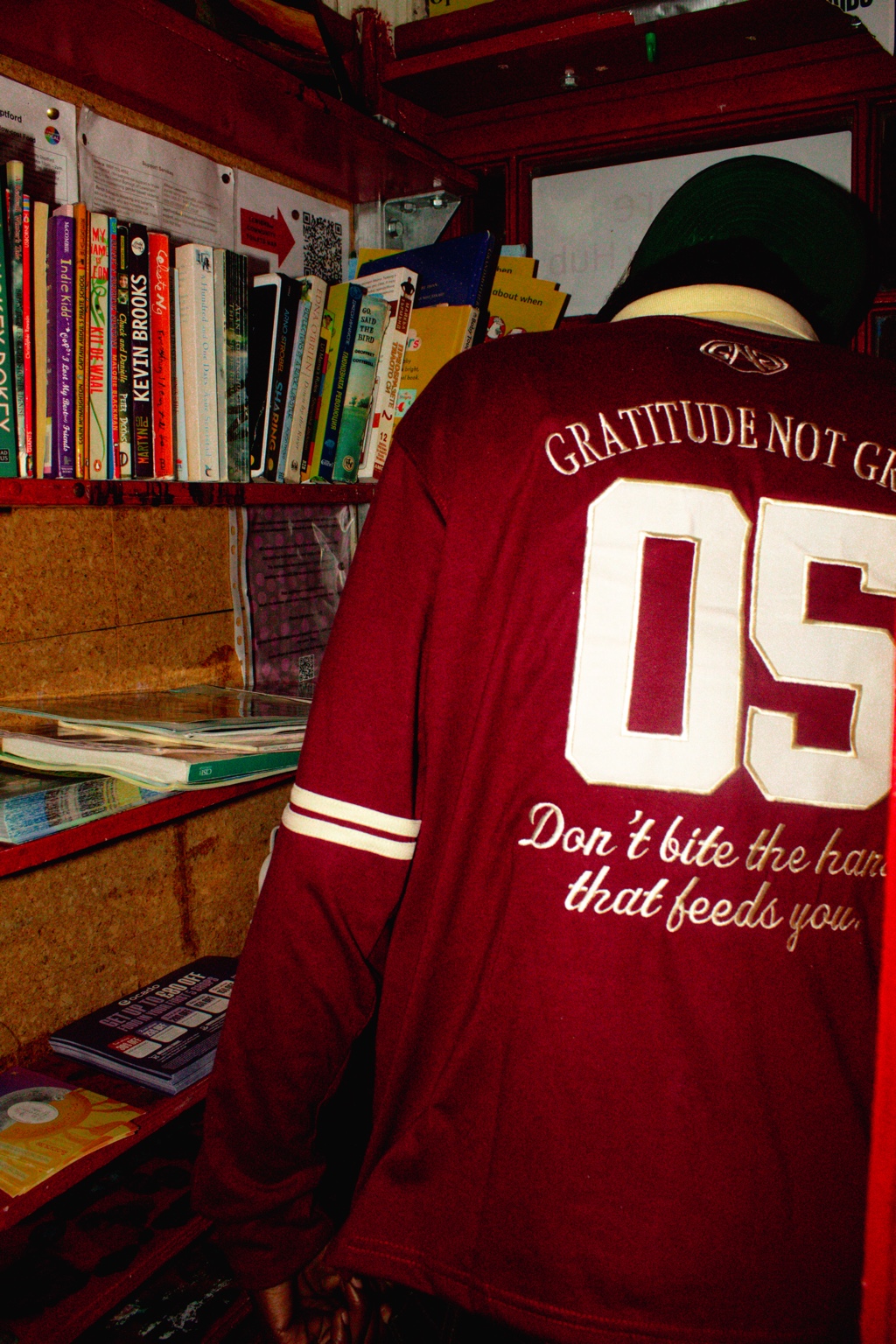 GNG campaign — 05 back of the burgundy rugby polo, Don't bite the hand that feeds you embroidery, at a London book exchange